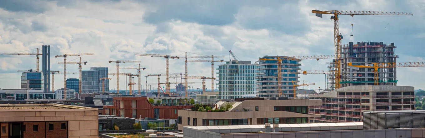 Panoramablick auf Großbaustelle mit mehr als zehn Baukränen und Rohbauten in urbaner Lage.