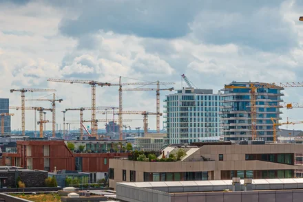 Panoramablick auf Großbaustelle mit mehr als zehn Baukränen und Rohbauten in urbaner Lage.
