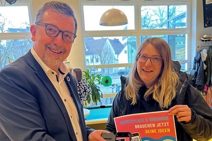 Julia Bade von der Stadtjugendpflege Bad Berleburg und Bürgermeister Bernd Fuhrmann mit einem Plakat zur Schnitzeljagd.