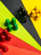 Grundlagenwissen für Ratsmitglieder Mehrere Spielfiguren in verschiedenen Farben sind gruppiert und voneinander getrennt angeordnet.