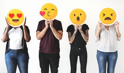 Menschen, die sich Emoticons vor das Gesicht halten