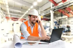 Foto eines Ingenieurs am Laptop auf einer Baustelle