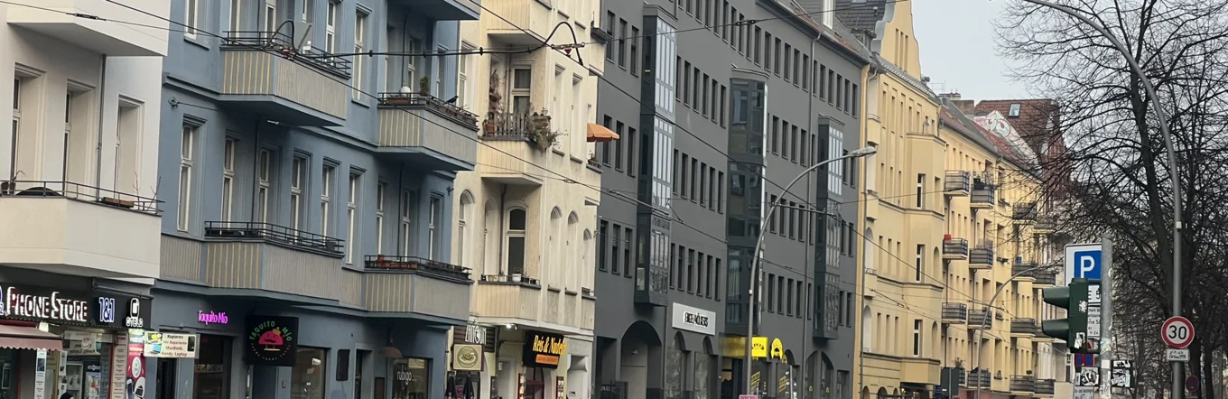 Innerstädtische Berliner Straße mit Altbauten, Kleingewerbe und Fußgängern an Wintertag