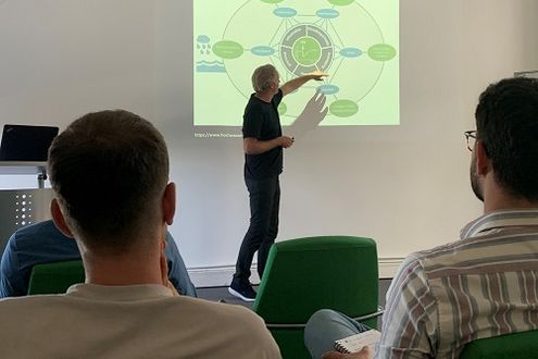 Prof. Dr. Christian Kuhlicke erklärt ein an die Wand projiziertes Schaubild bei der Veranstaltungsreihe vhw & friends