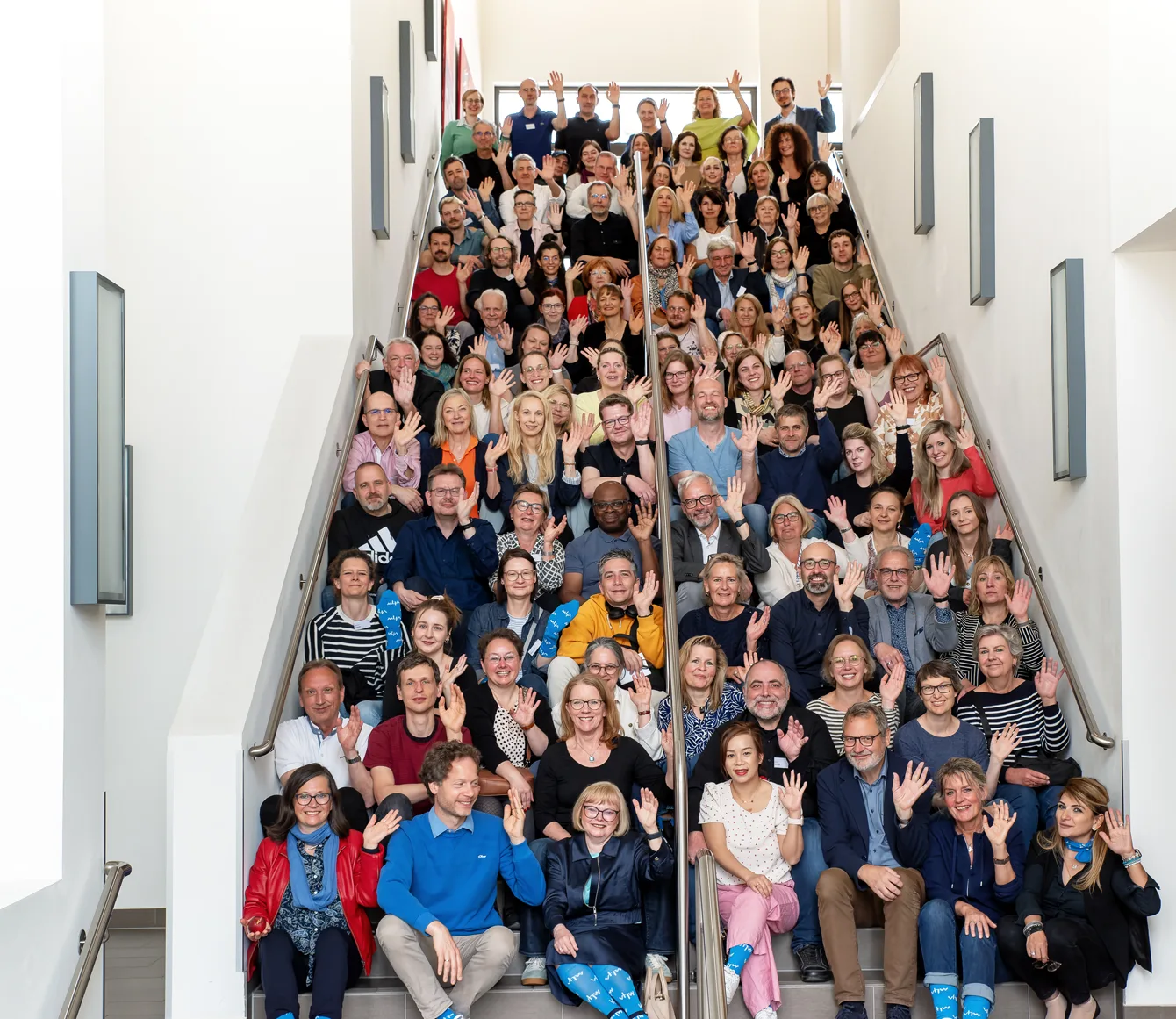 rund 100 Mitarbeitende des vhw sitzen auf einer Treppe
