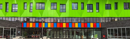 Foto der bunten Fassade eines modernen Schulgebäudes.