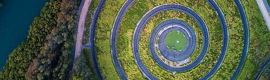 Luftbild eines als Schnecke geformten Weges in der Nähe eines Gewässers.