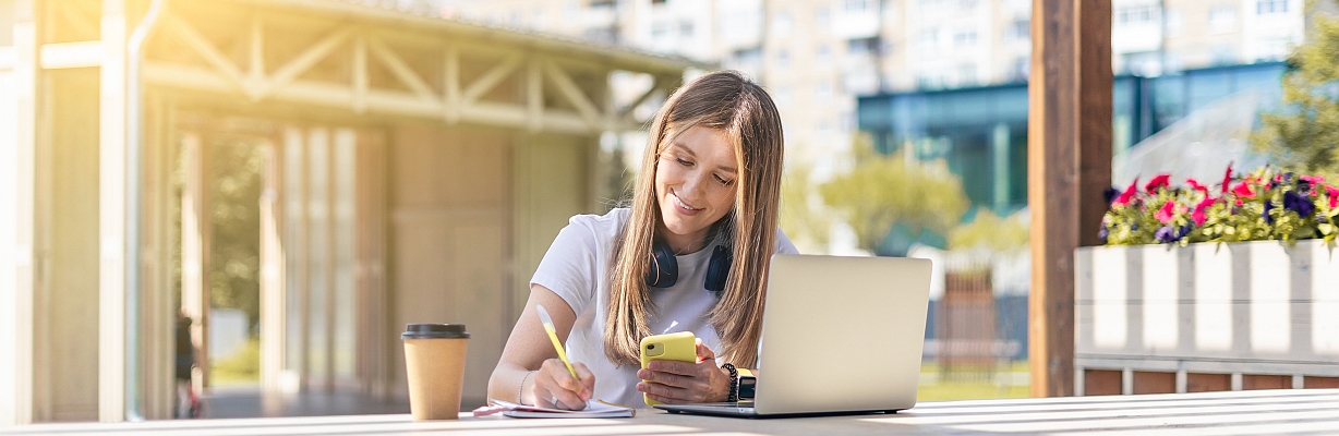 Junge Frau beim E-Learning mit Laptop im Freien